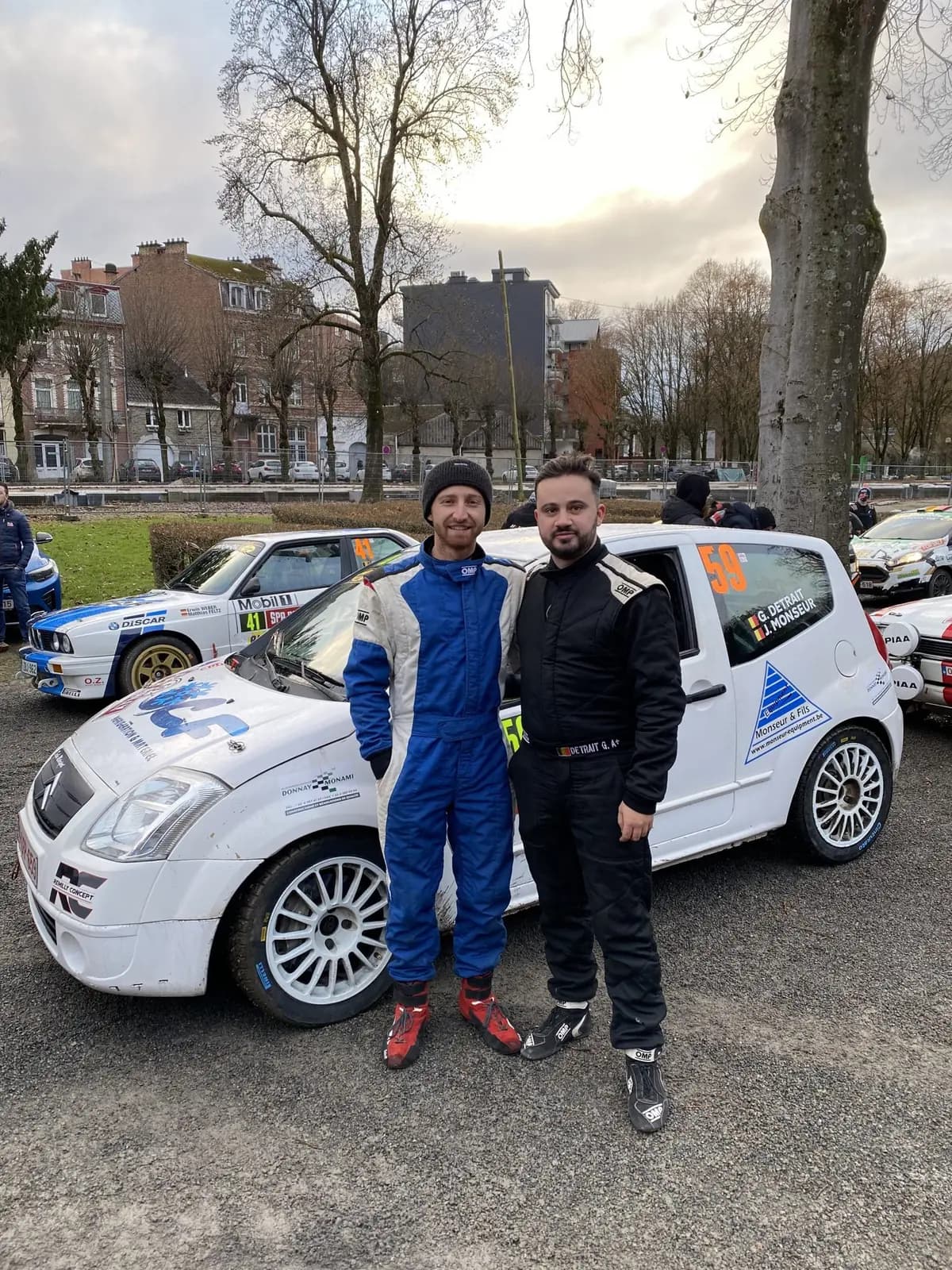 Jonathan Monseur en combinaison devant sa voiture de course au parc fermé